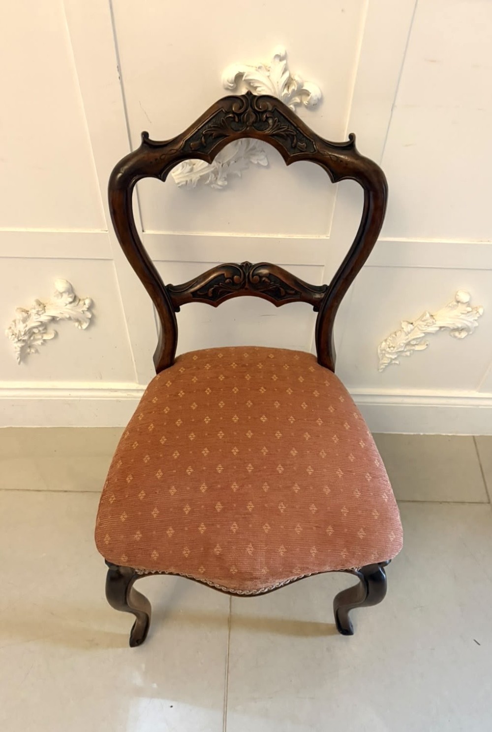 A pair of Victorian carved walnut side chairs featuring open balloon backs with foliate carvings, cabriole legs, and terracotta patterned fabric upholstered seats. View VIII