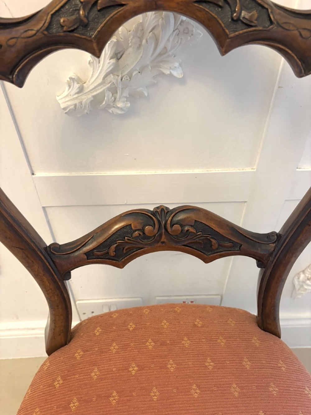 A pair of Victorian carved walnut side chairs featuring open balloon backs with foliate carvings, cabriole legs, and terracotta patterned fabric upholstered seats. View X