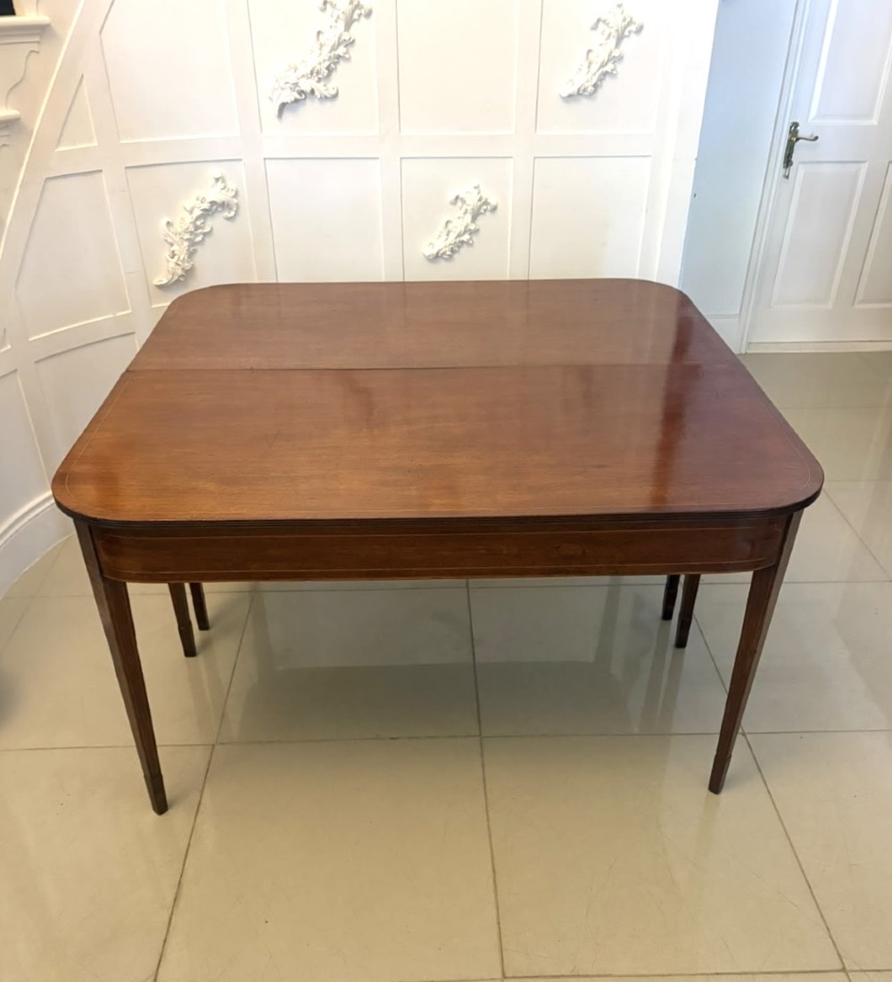 A pair of Georgian mahogany console tables featuring rounded corners, inlaid aprons, and slender tapered legs. View V