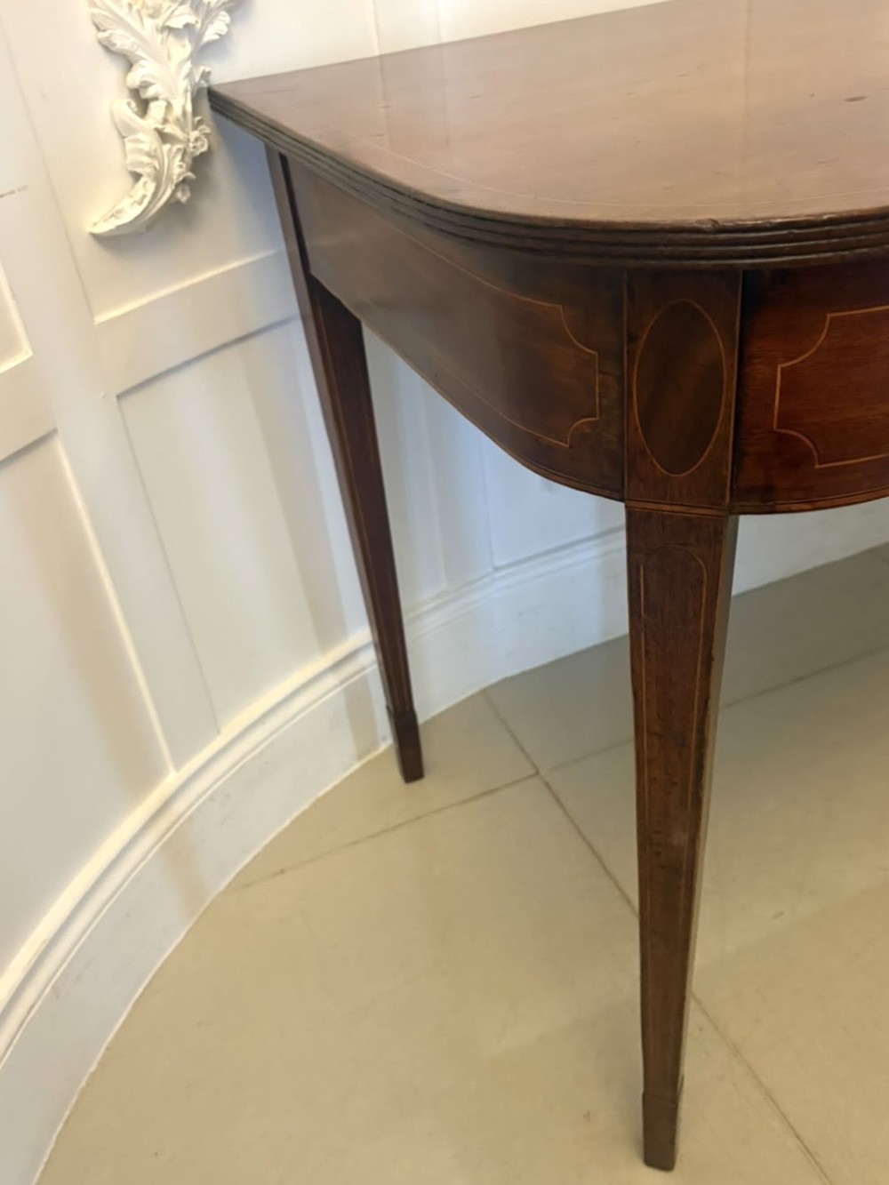 A pair of Georgian mahogany console tables featuring rounded corners, inlaid aprons, and slender tapered legs. View VII