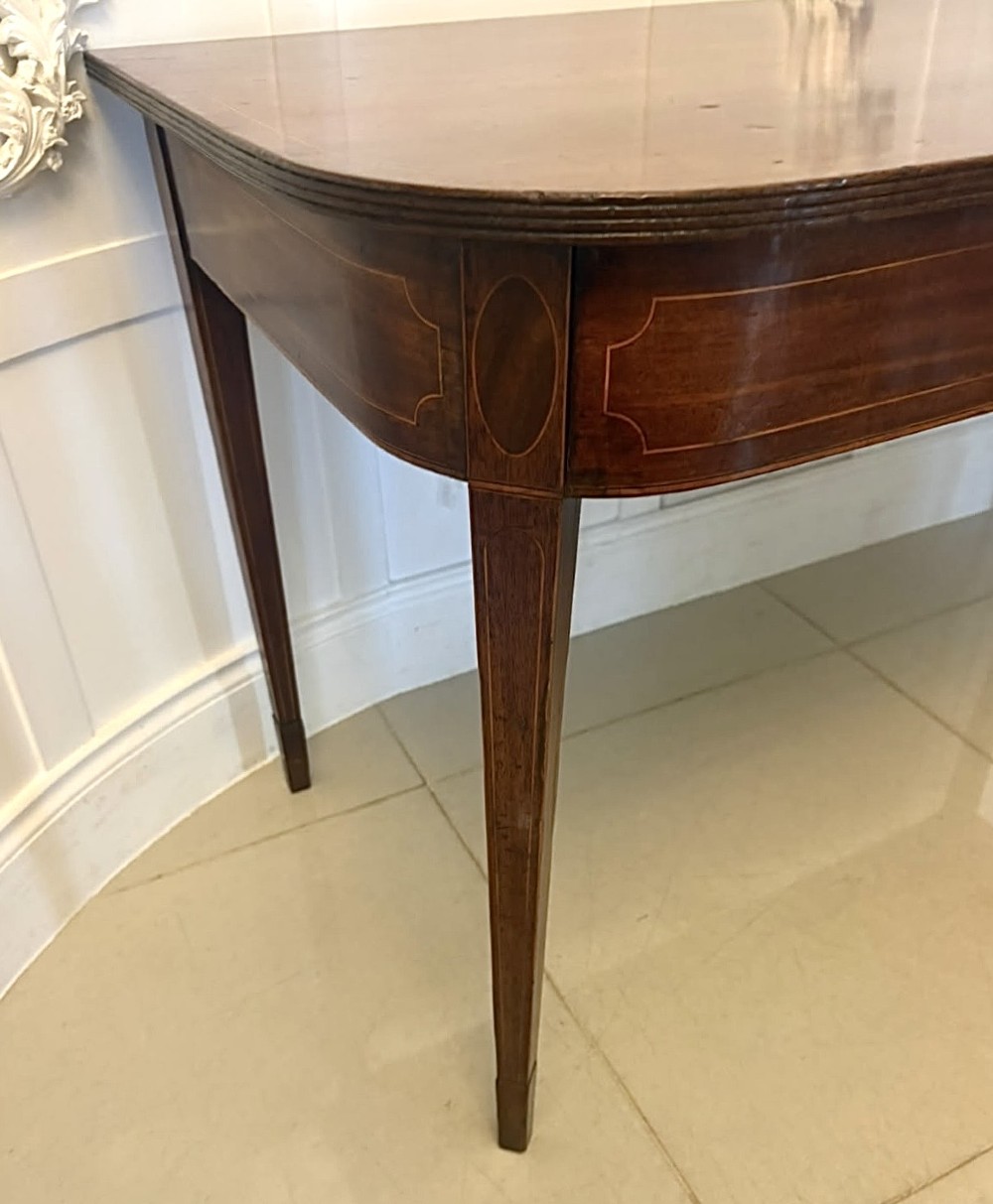 A pair of Georgian mahogany console tables featuring rounded corners, inlaid aprons, and slender tapered legs. View VIII