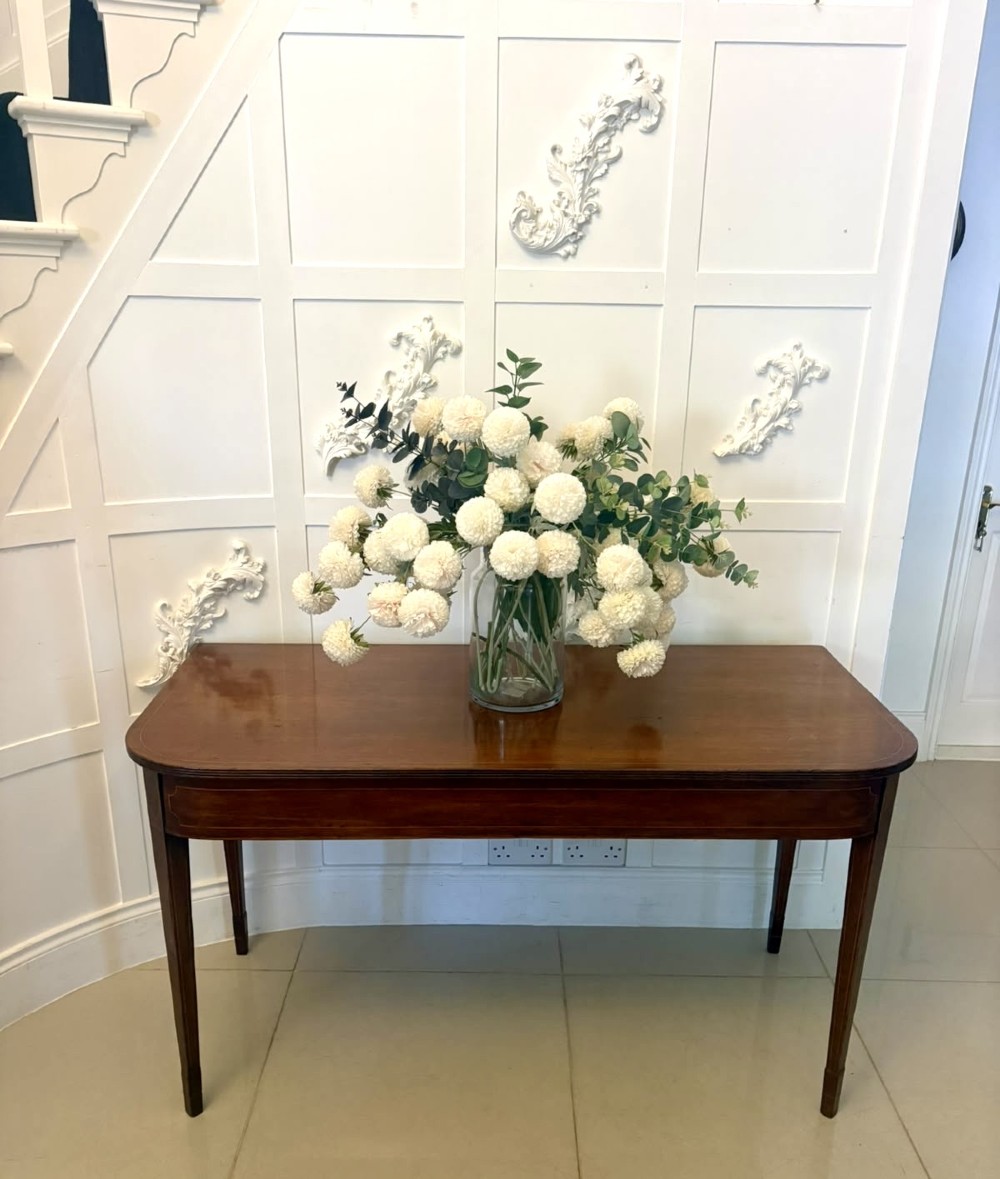 A pair of Georgian mahogany console tables featuring rounded corners, inlaid aprons, and slender tapered legs. View XI