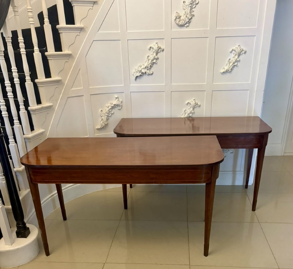 A pair of Georgian mahogany console tables featuring rounded corners, inlaid aprons, and slender tapered legs. View XIII