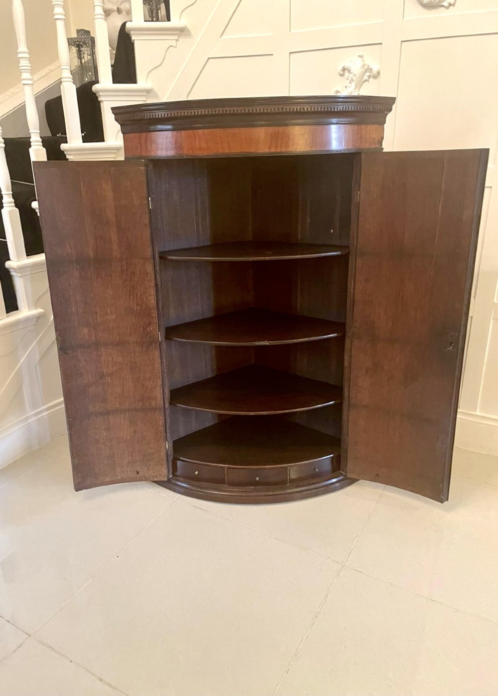 An 18th-century George III bow-fronted corner cabinet crafted from plum pudding mahogany with brass H-hinges. View V