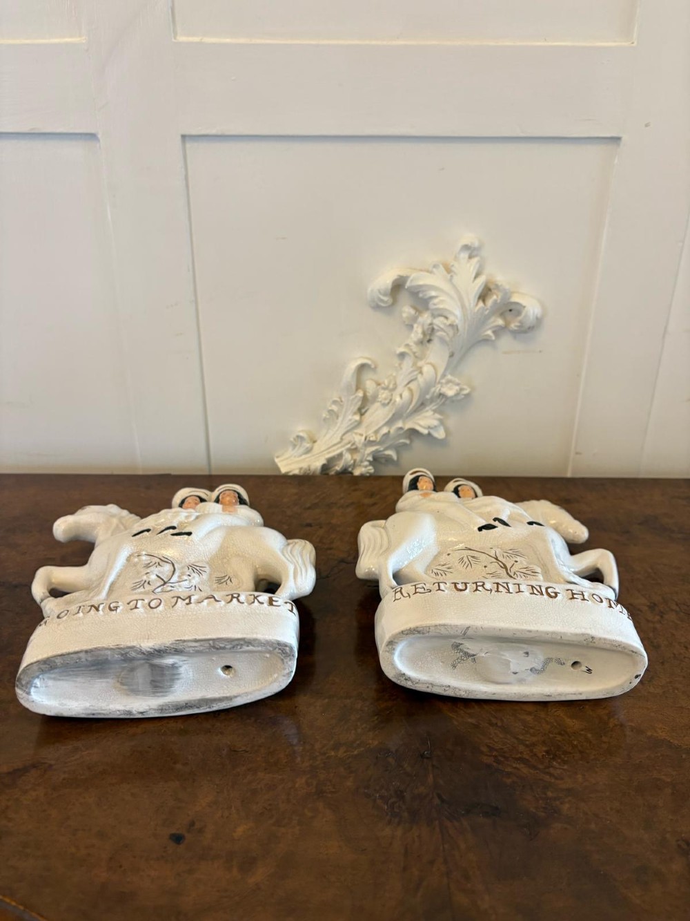 A pair of off-white antique Staffordshire flatback ceramic figures featuring riders on horseback titled Going to Market and Returning Home. View II
