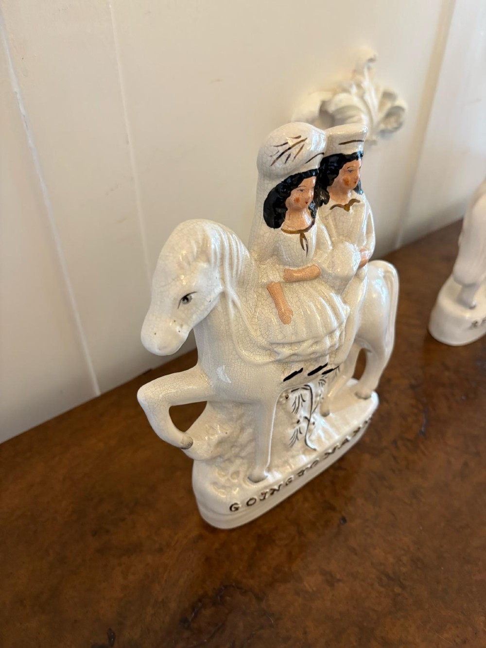 A pair of off-white antique Staffordshire flatback ceramic figures featuring riders on horseback titled Going to Market and Returning Home. View V