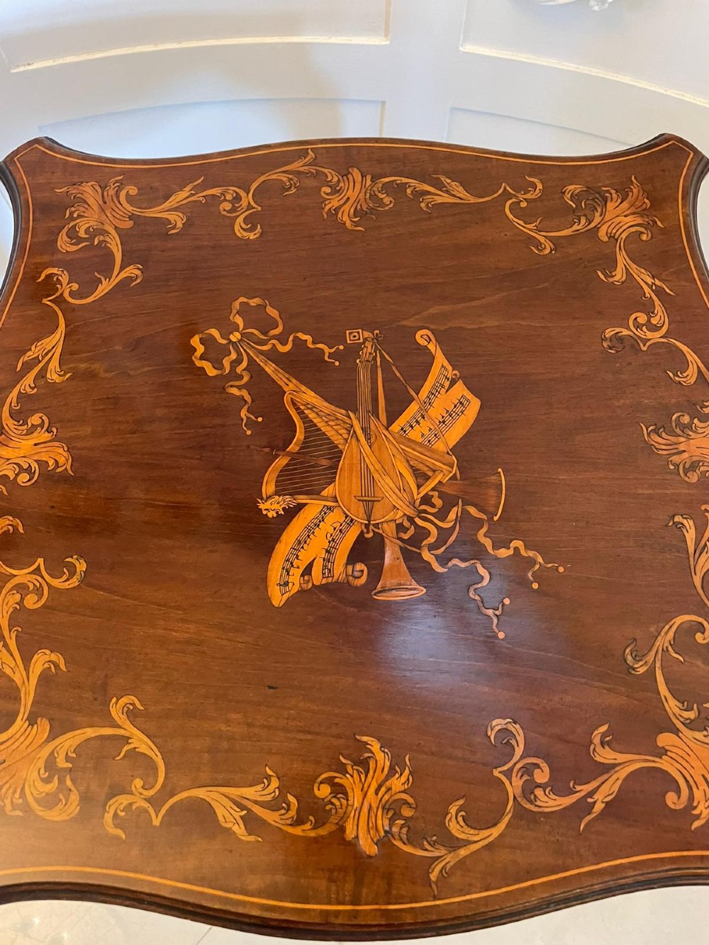 A Victorian mahogany side table featuring detailed marquetry inlay of musical instruments on a serpentine top supported by four cabriole legs. View II