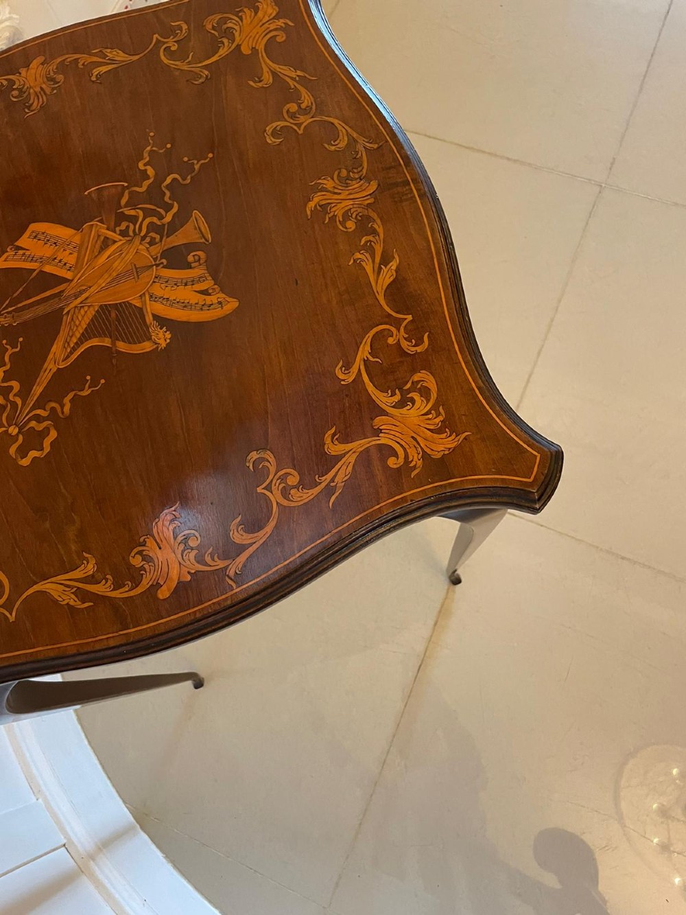 A Victorian mahogany side table featuring detailed marquetry inlay of musical instruments on a serpentine top supported by four cabriole legs. View IV
