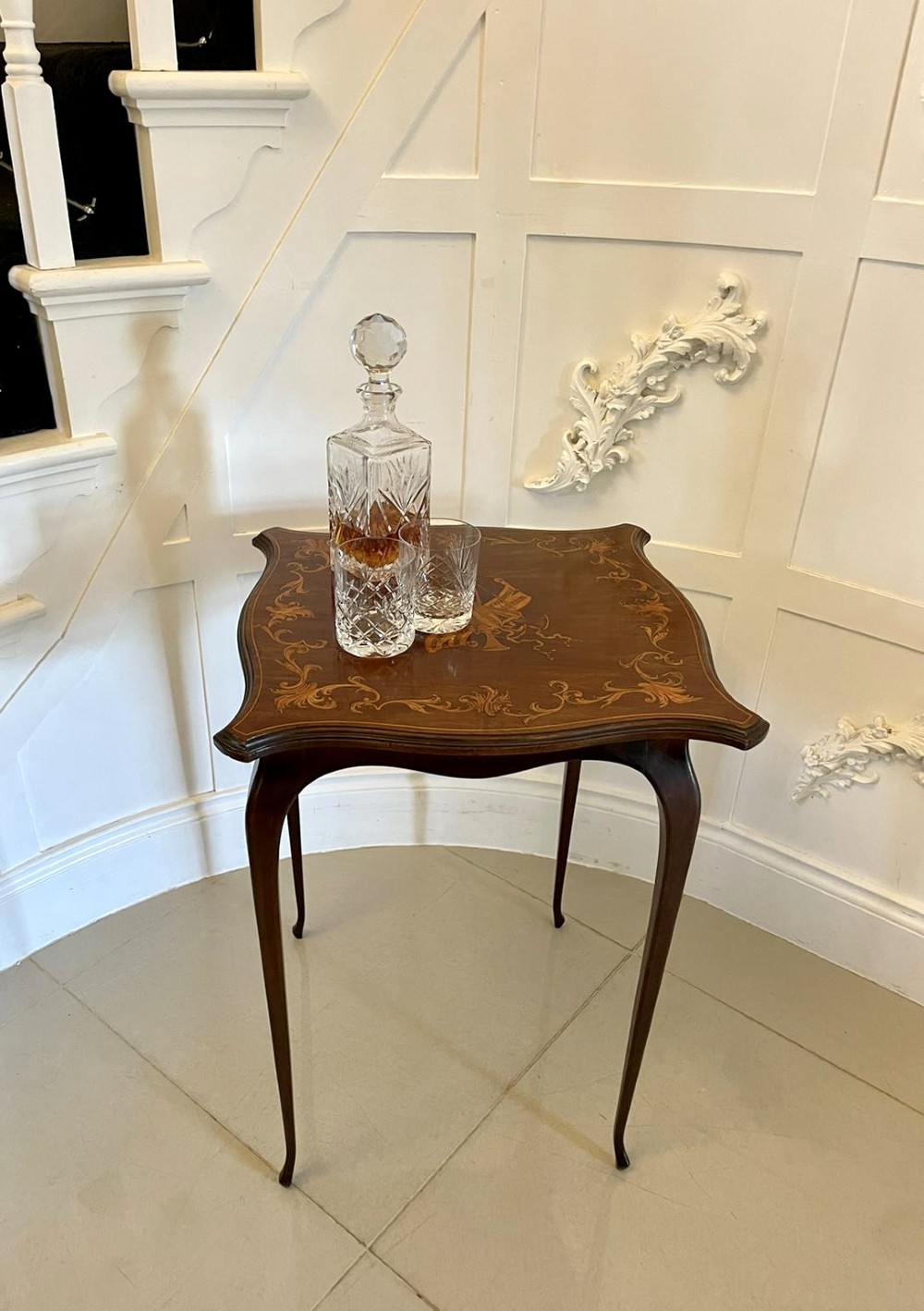 A Victorian mahogany side table featuring detailed marquetry inlay of musical instruments on a serpentine top supported by four cabriole legs. View V