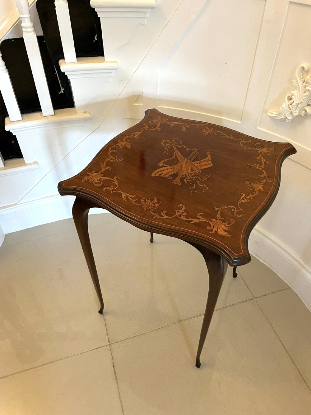 A Victorian mahogany side table featuring detailed marquetry inlay of musical instruments on a serpentine top supported by four cabriole legs. View XII