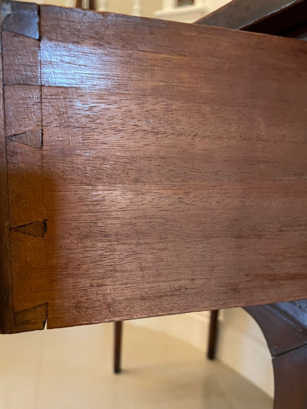 An Edwardian inlaid mahogany serpentine sideboard featuring a central drawer, flanking cupboard doors, brass circular handles, and tapered legs. View IV