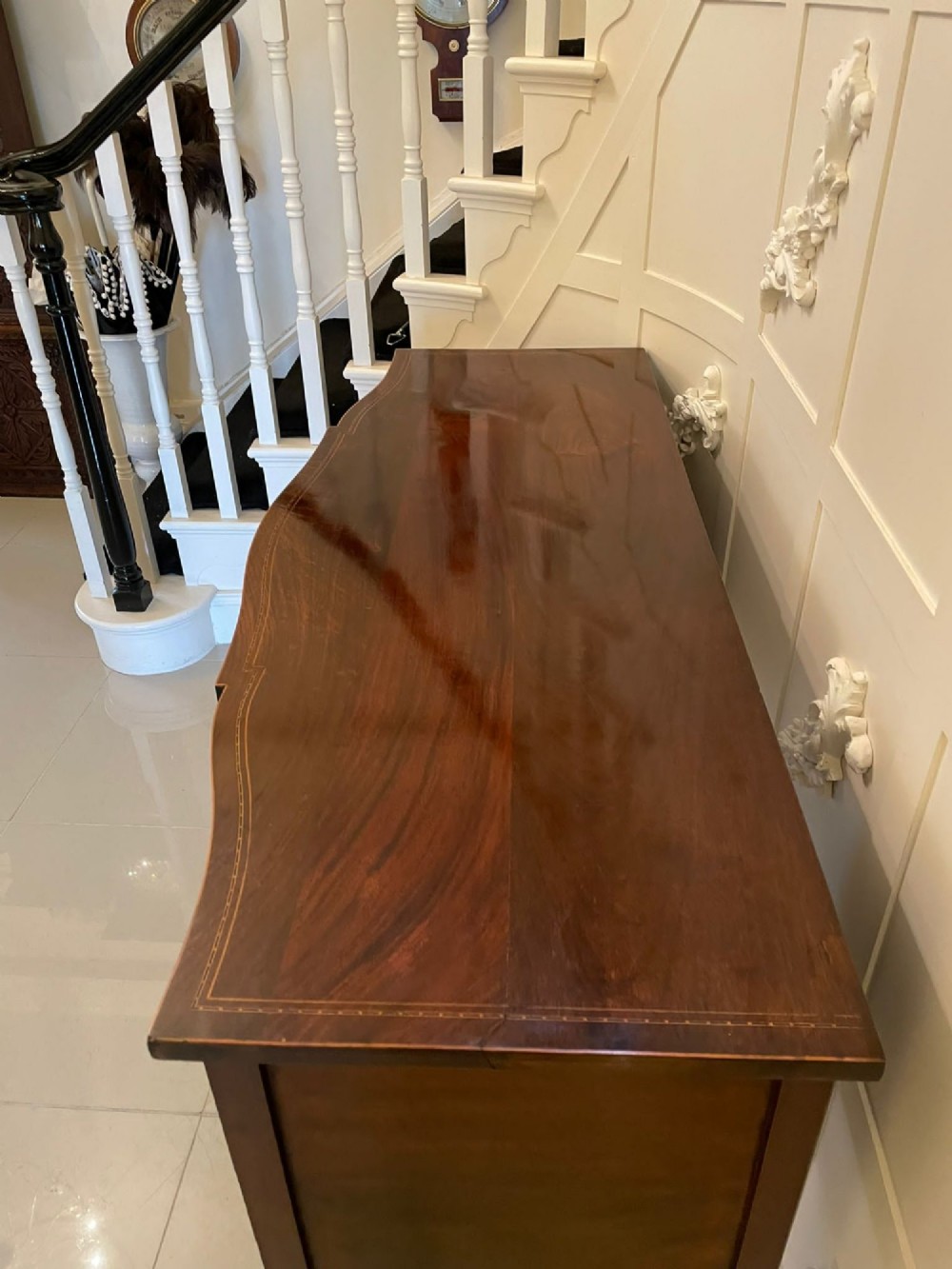An Edwardian inlaid mahogany serpentine sideboard featuring a central drawer, flanking cupboard doors, brass circular handles, and tapered legs. View XIII