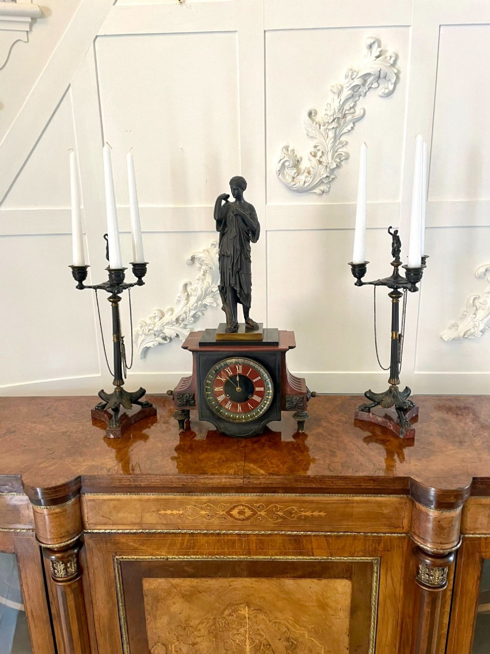 A Regency bronze and marble clock set featuring a central figure-topped mantel clock flanked by a pair of three-branch candelabra.