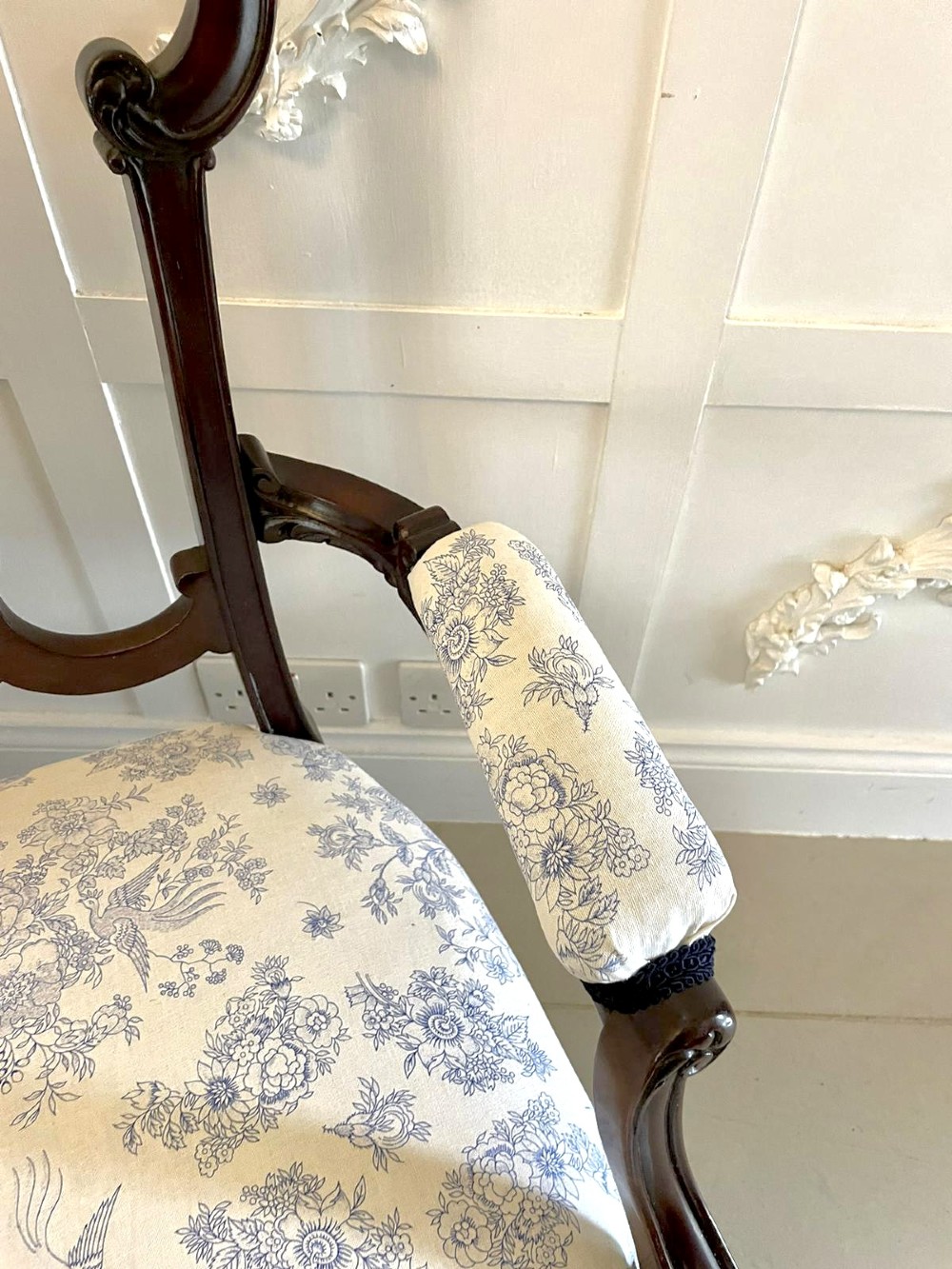A Victorian carved mahogany settee featuring upholstered blue and white floral pattern seat and backrest, padded armrests, and carved cabriole legs. View VIII