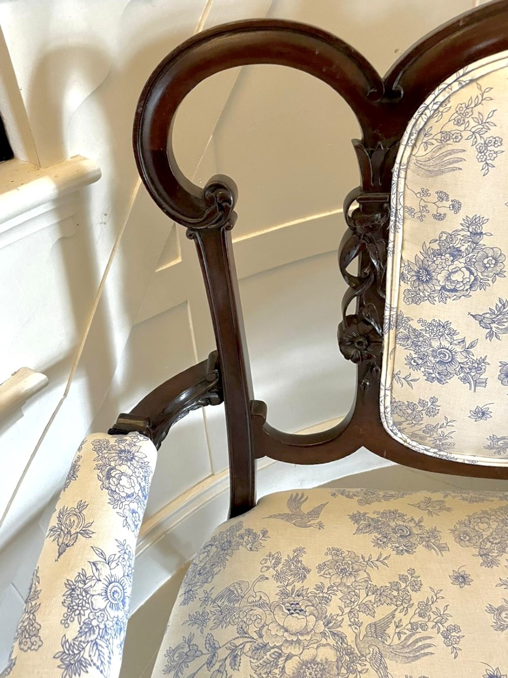 A Victorian carved mahogany settee featuring upholstered blue and white floral pattern seat and backrest, padded armrests, and carved cabriole legs. View XI
