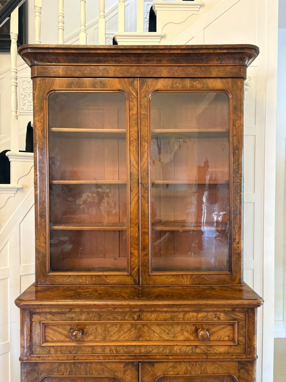 A Victorian burr walnut secretaire bookcase featuring a glazed upper cabinet with two doors, a deep secretaire drawer with turned wooden handles, and a two-door cupboard base. View IV