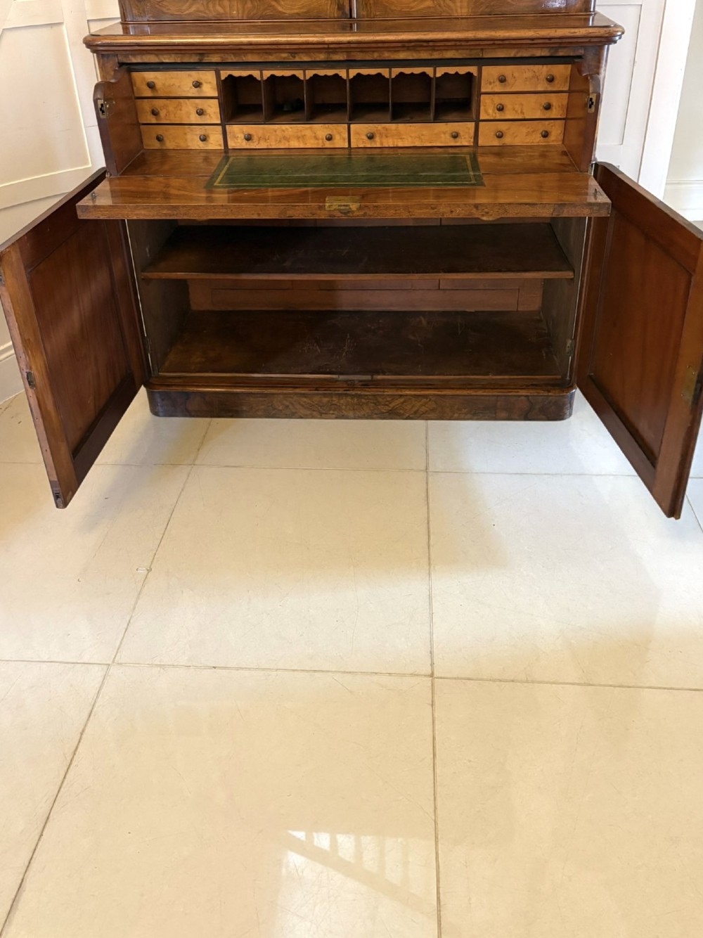 A Victorian burr walnut secretaire bookcase featuring a glazed upper cabinet with two doors, a deep secretaire drawer with turned wooden handles, and a two-door cupboard base. View VI