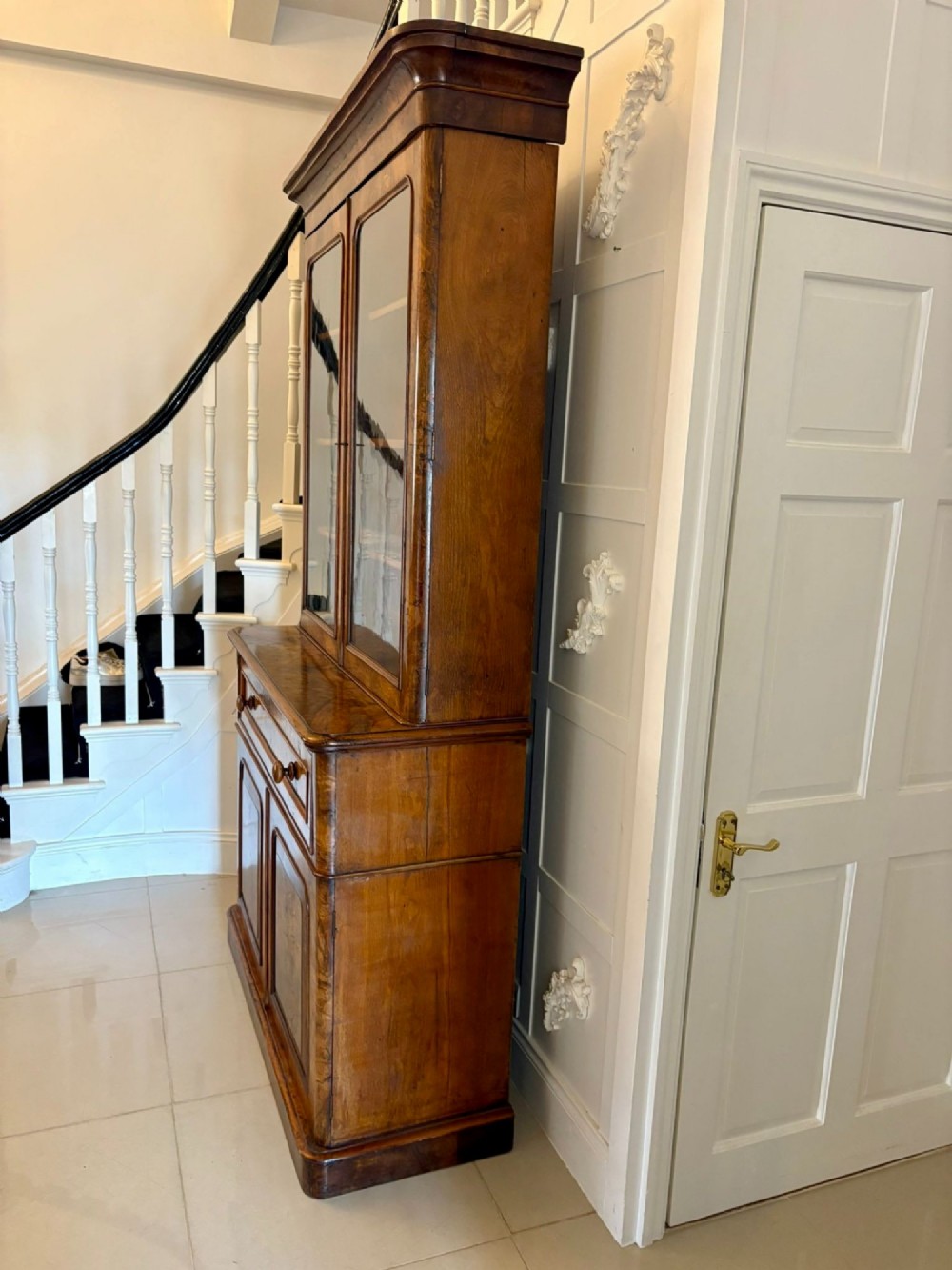 A Victorian burr walnut secretaire bookcase featuring a glazed upper cabinet with two doors, a deep secretaire drawer with turned wooden handles, and a two-door cupboard base. View IX