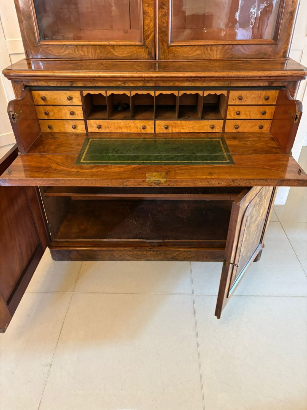 A Victorian burr walnut secretaire bookcase featuring a glazed upper cabinet with two doors, a deep secretaire drawer with turned wooden handles, and a two-door cupboard base. View X