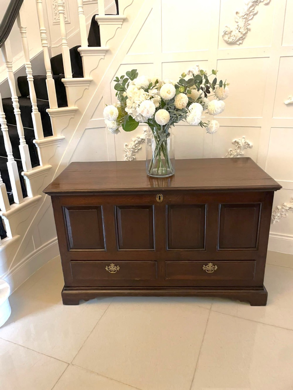 An 18th-century dark oak mule chest featuring four panelled facade sections above two lower drawers with brass handles. View IV