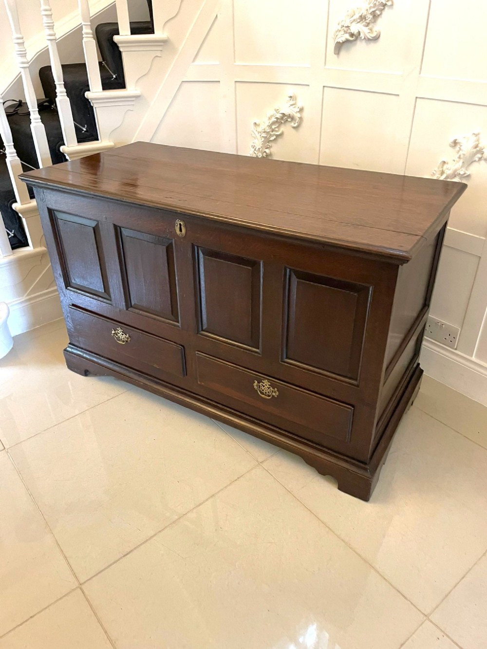 An 18th-century dark oak mule chest featuring four panelled facade sections above two lower drawers with brass handles. View VIII
