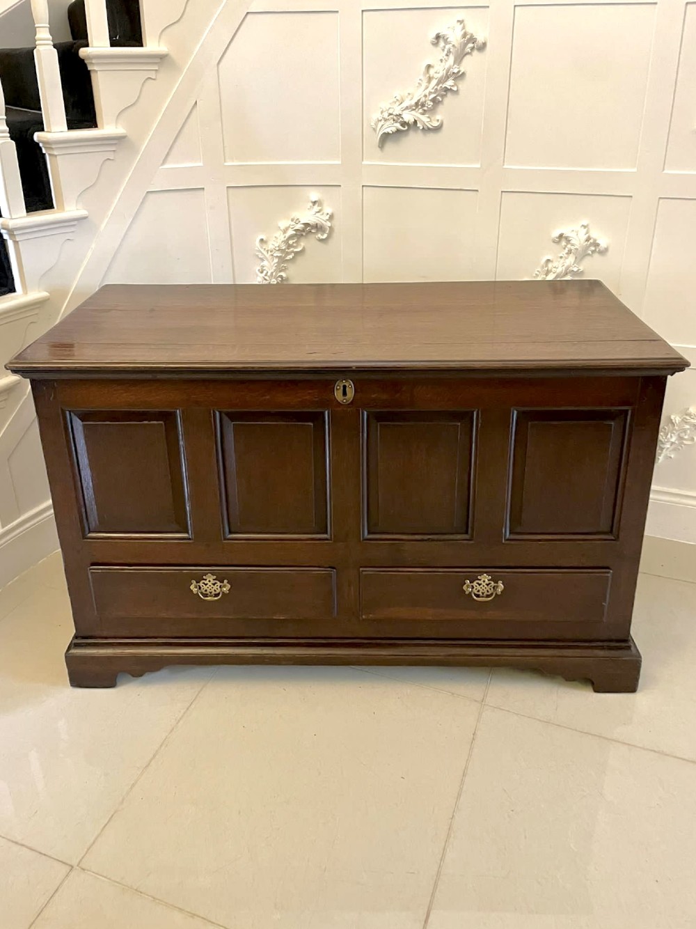 An 18th-century dark oak mule chest featuring four panelled facade sections above two lower drawers with brass handles. View IX