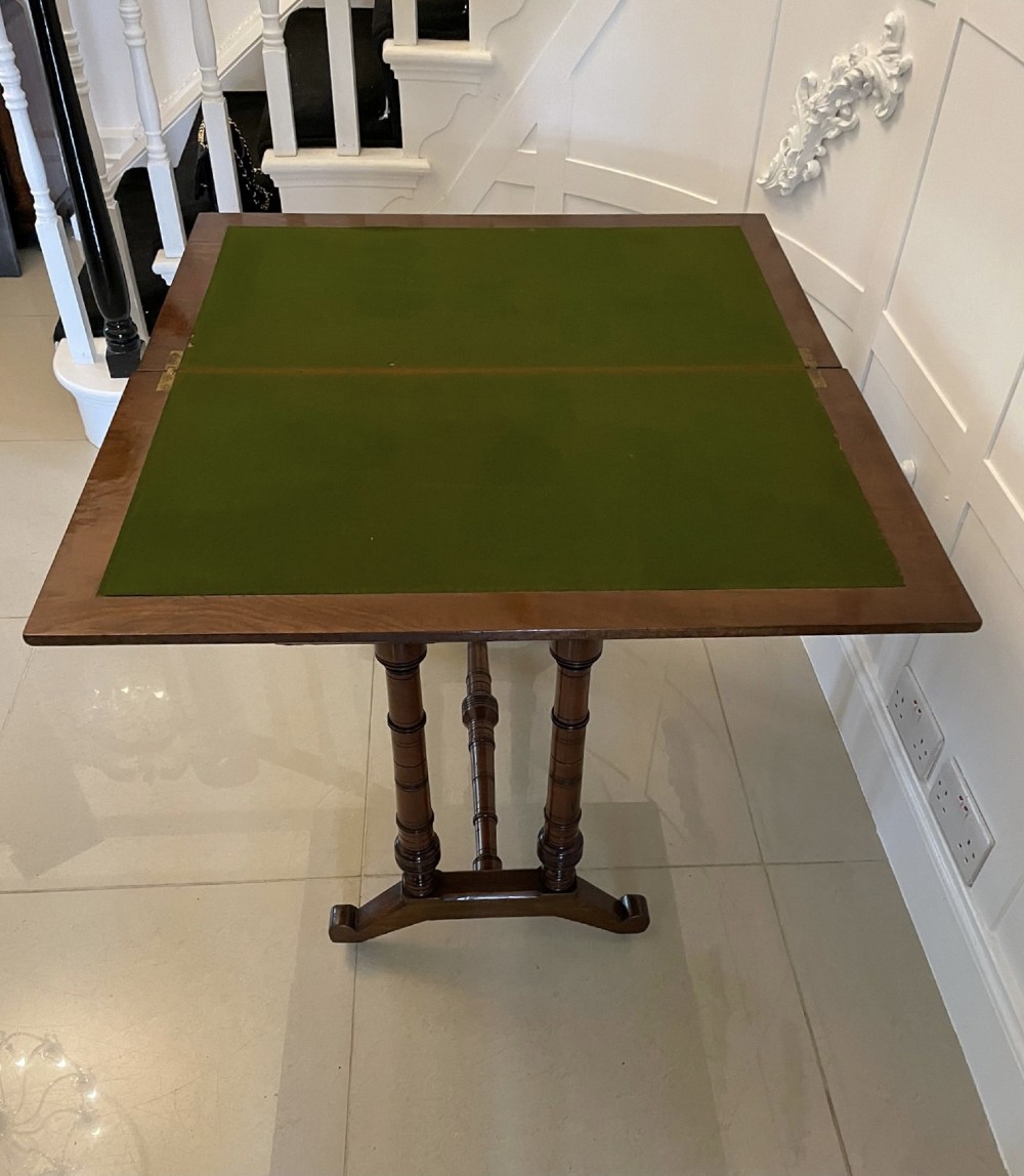 An Arts and Crafts oak side table featuring dark ebony inlay around the rectangular fold-over top, dual turned legs on a stretcher base, and ceramic castors. View III