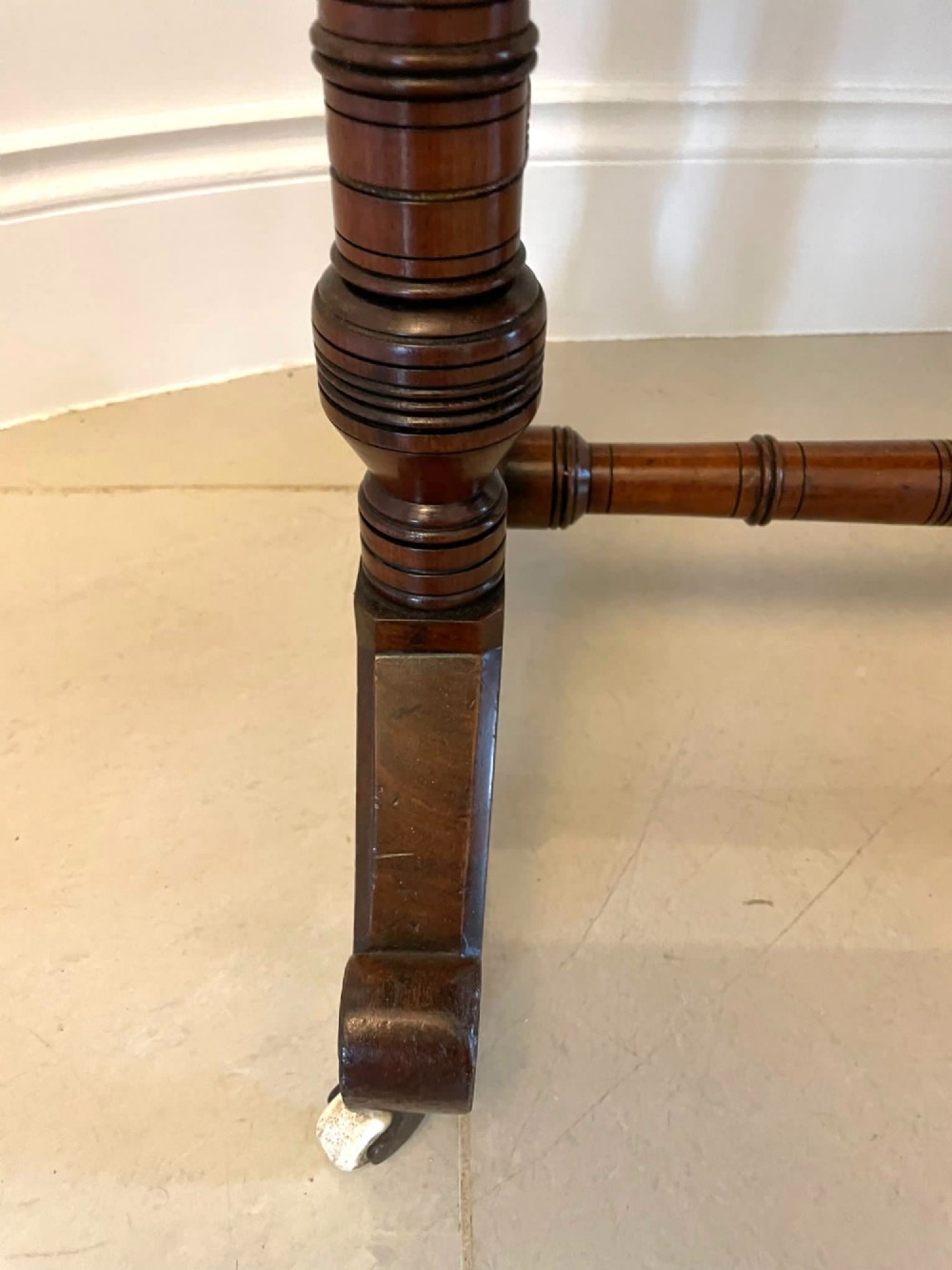 An Arts and Crafts oak side table featuring dark ebony inlay around the rectangular fold-over top, dual turned legs on a stretcher base, and ceramic castors. View IV