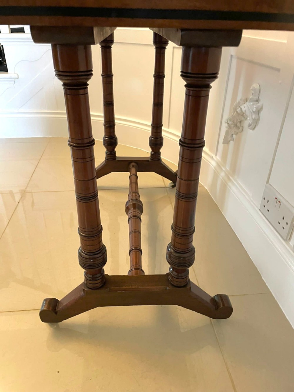 An Arts and Crafts oak side table featuring dark ebony inlay around the rectangular fold-over top, dual turned legs on a stretcher base, and ceramic castors. View VIII
