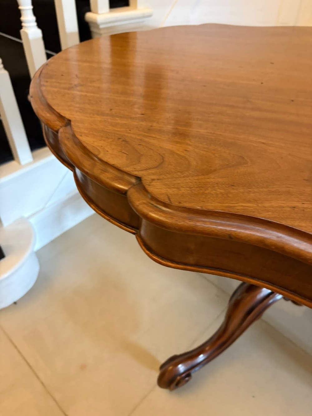 A Victorian figured mahogany tilt-top centre table featuring a shaped serpentine top positioned vertically on a carved central pedestal with four splayed legs. View IV