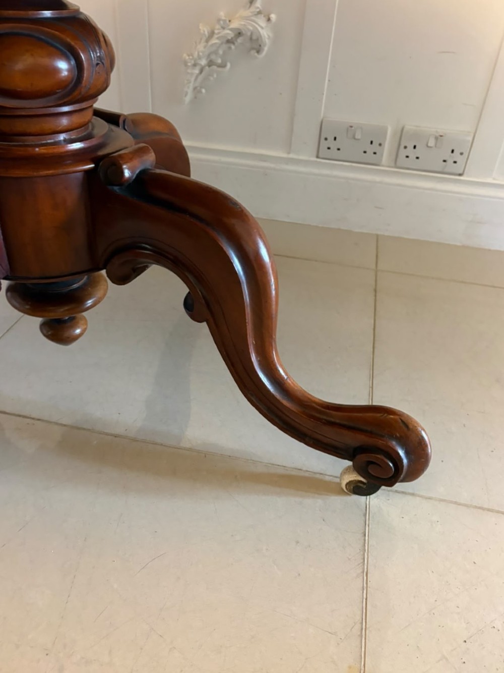 A Victorian figured mahogany tilt-top centre table featuring a shaped serpentine top positioned vertically on a carved central pedestal with four splayed legs. View VIII