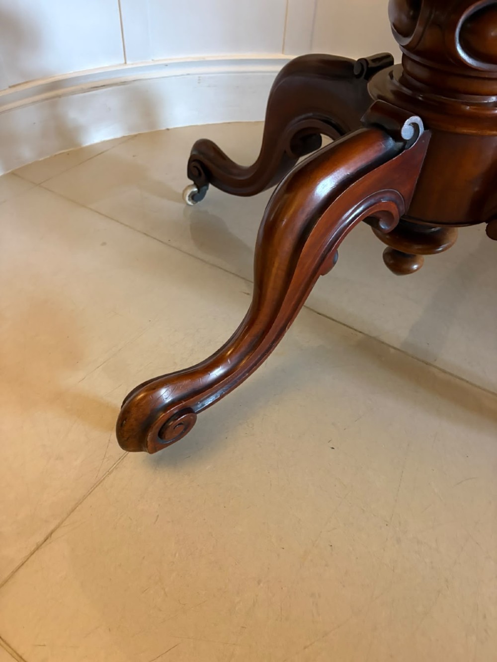 A Victorian figured mahogany tilt-top centre table featuring a shaped serpentine top positioned vertically on a carved central pedestal with four splayed legs. View X