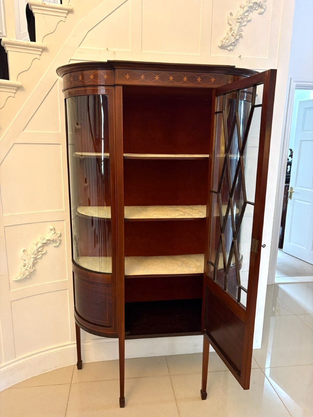 An Edwardian mahogany display cabinet featuring bow-ended glass sides, a central astragal glazed door, and satinwood marquetry inlay. View V