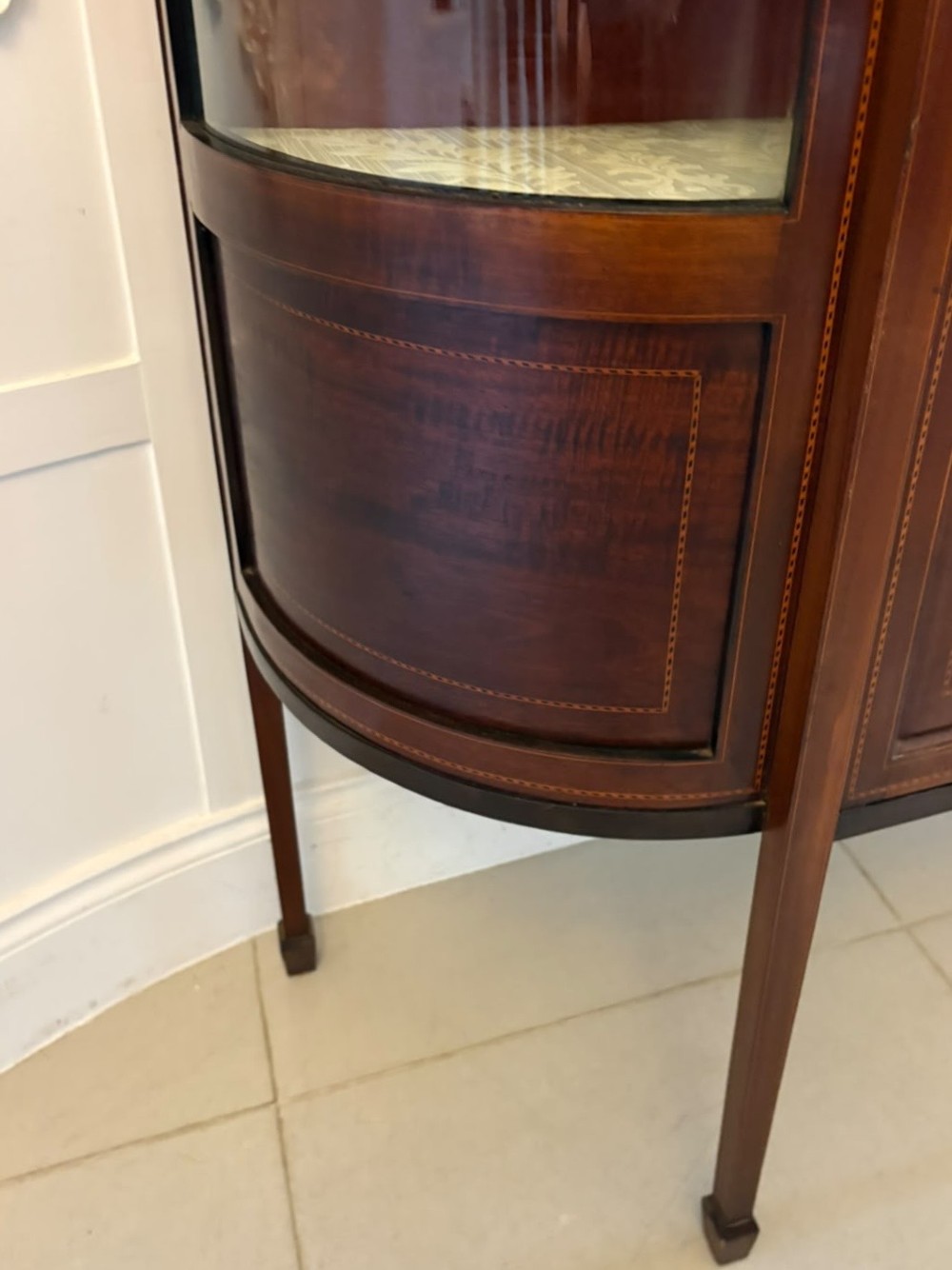 An Edwardian mahogany display cabinet featuring bow-ended glass sides, a central astragal glazed door, and satinwood marquetry inlay. View VII