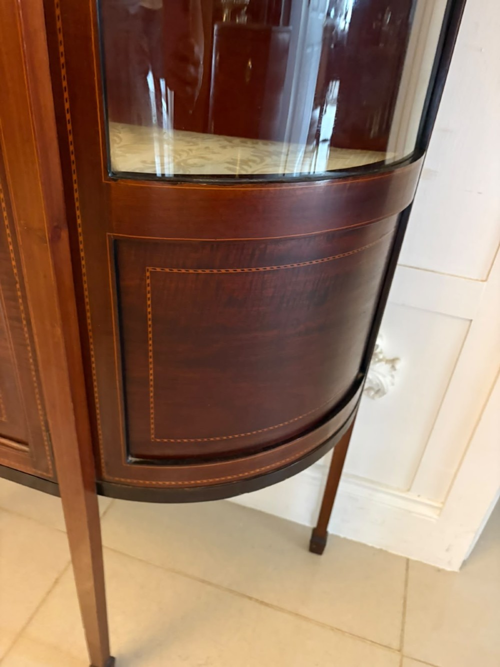 An Edwardian mahogany display cabinet featuring bow-ended glass sides, a central astragal glazed door, and satinwood marquetry inlay. View IX
