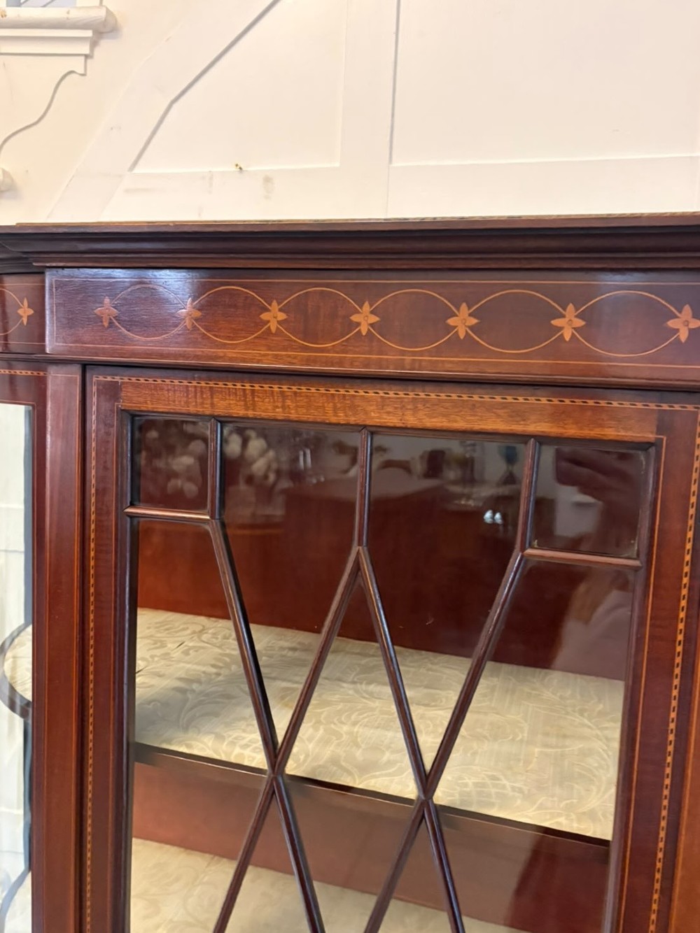 An Edwardian mahogany display cabinet featuring bow-ended glass sides, a central astragal glazed door, and satinwood marquetry inlay. View XII
