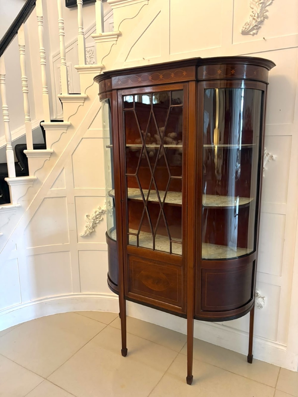 An Edwardian mahogany display cabinet featuring bow-ended glass sides, a central astragal glazed door, and satinwood marquetry inlay. View XIV