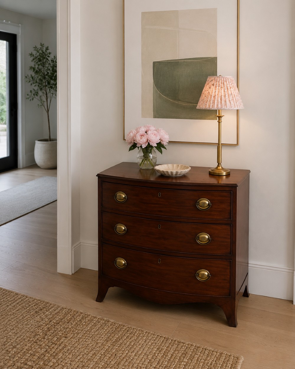 An antique Georgian mahogany bow-front chest featuring three graduating drawers with brass oval handles, supported on splayed feet. View II