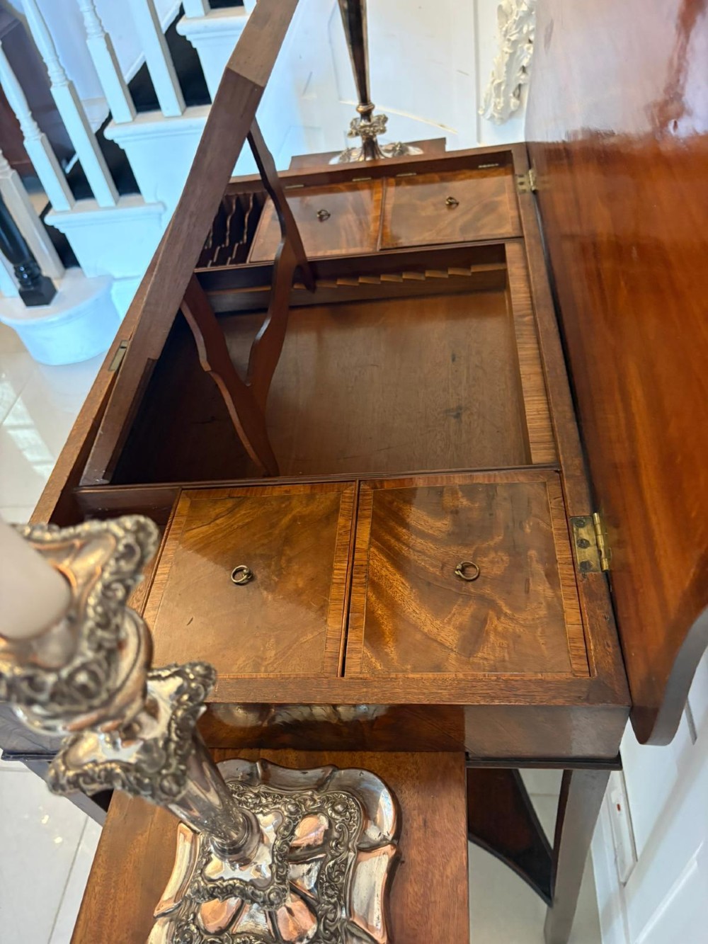 An antique mahogany dressing table with an open hinged lid displaying an internal mirror, storage compartments, side slides, and a shaped lower shelf. View V