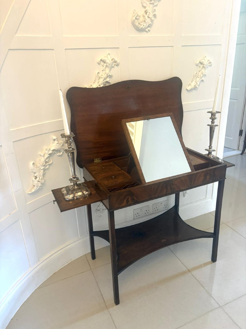 An antique mahogany dressing table with an open hinged lid displaying an internal mirror, storage compartments, side slides, and a shaped lower shelf. View VII