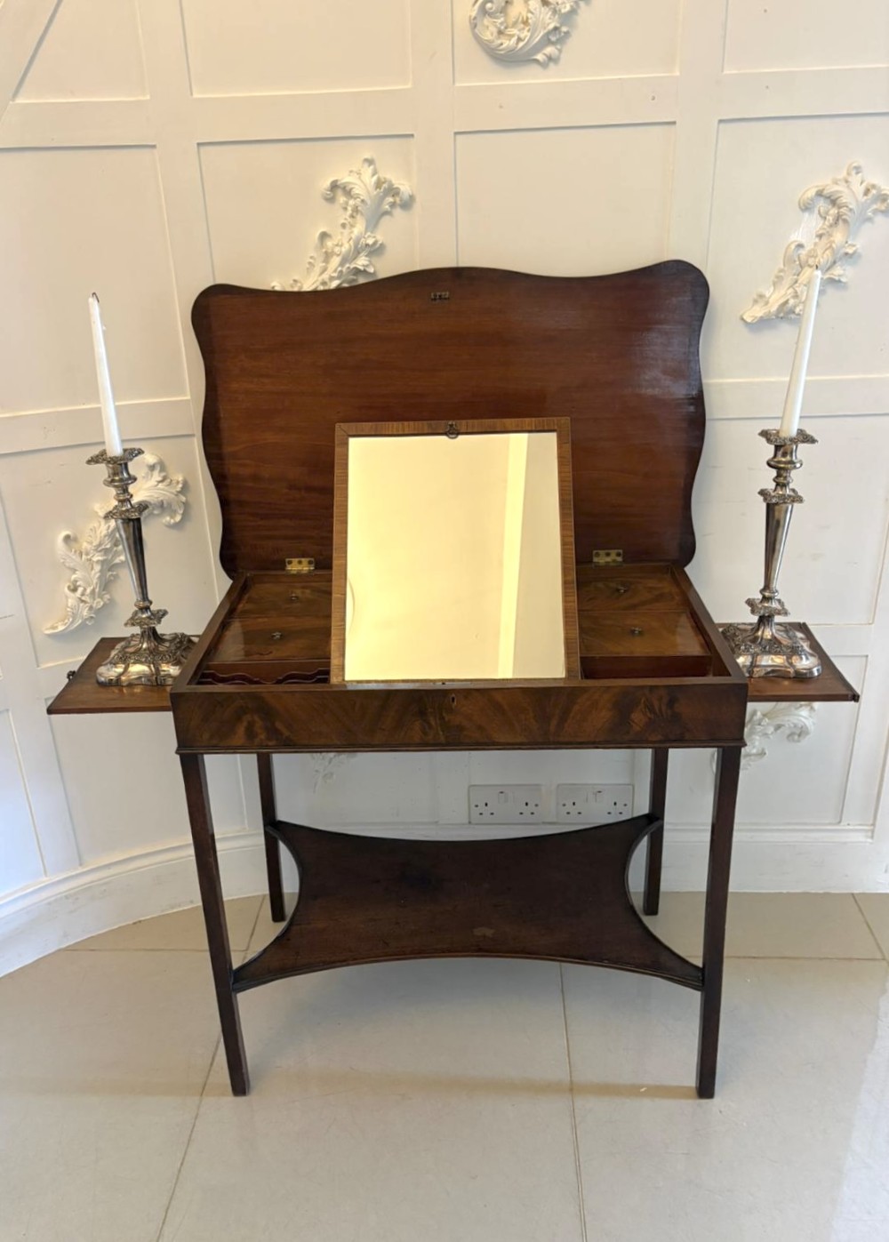 An antique mahogany dressing table with an open hinged lid displaying an internal mirror, storage compartments, side slides, and a shaped lower shelf. View IX
