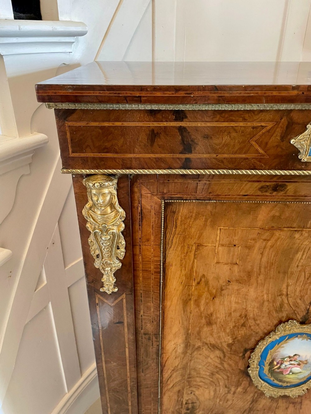 A pair of Victorian burr walnut pier cabinets featuring inlaid wood borders, gilt-bronze mounts, and central oval painted porcelain plaques. View VI
