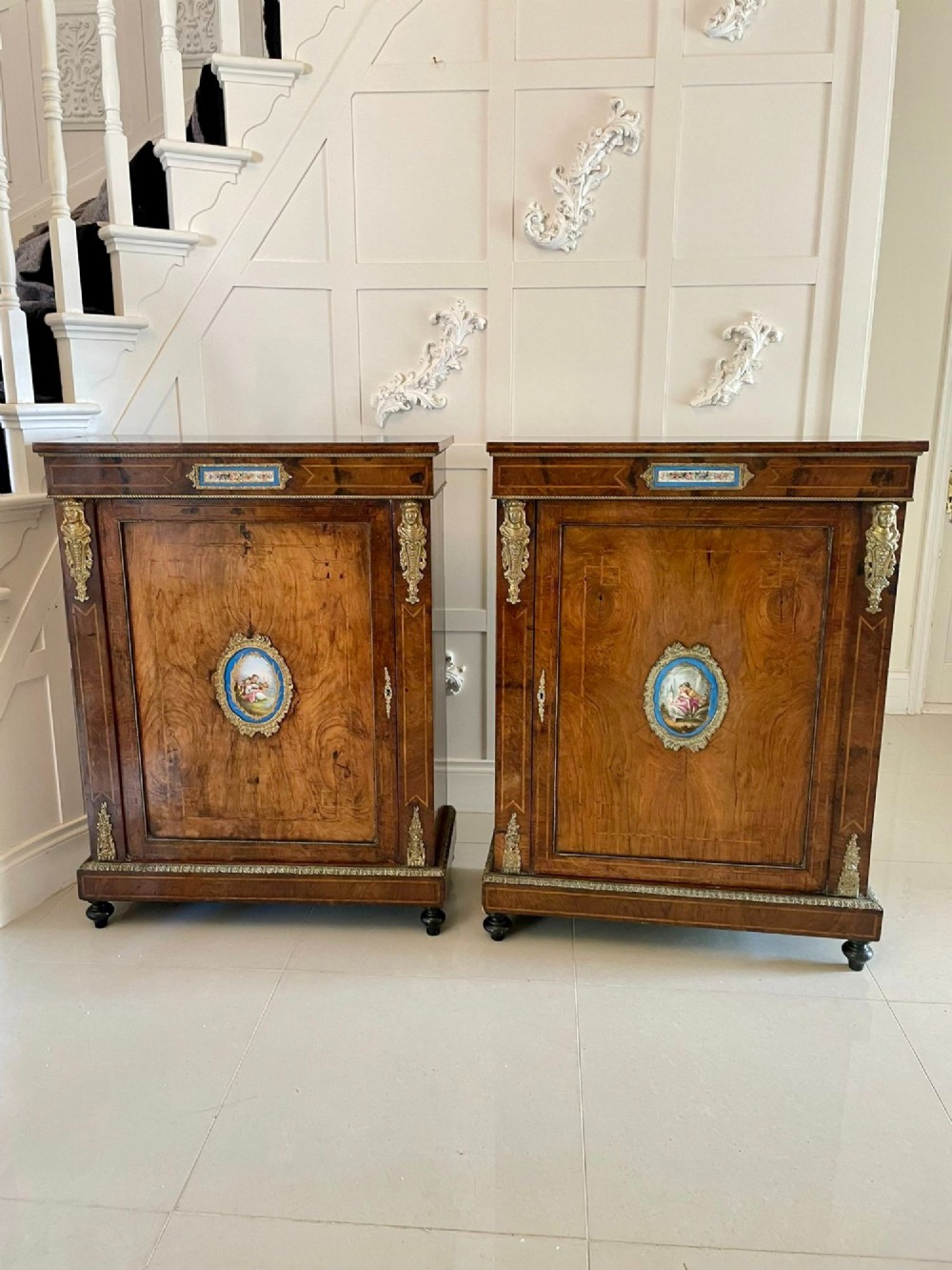 A pair of Victorian burr walnut pier cabinets featuring inlaid wood borders, gilt-bronze mounts, and central oval painted porcelain plaques. View IX