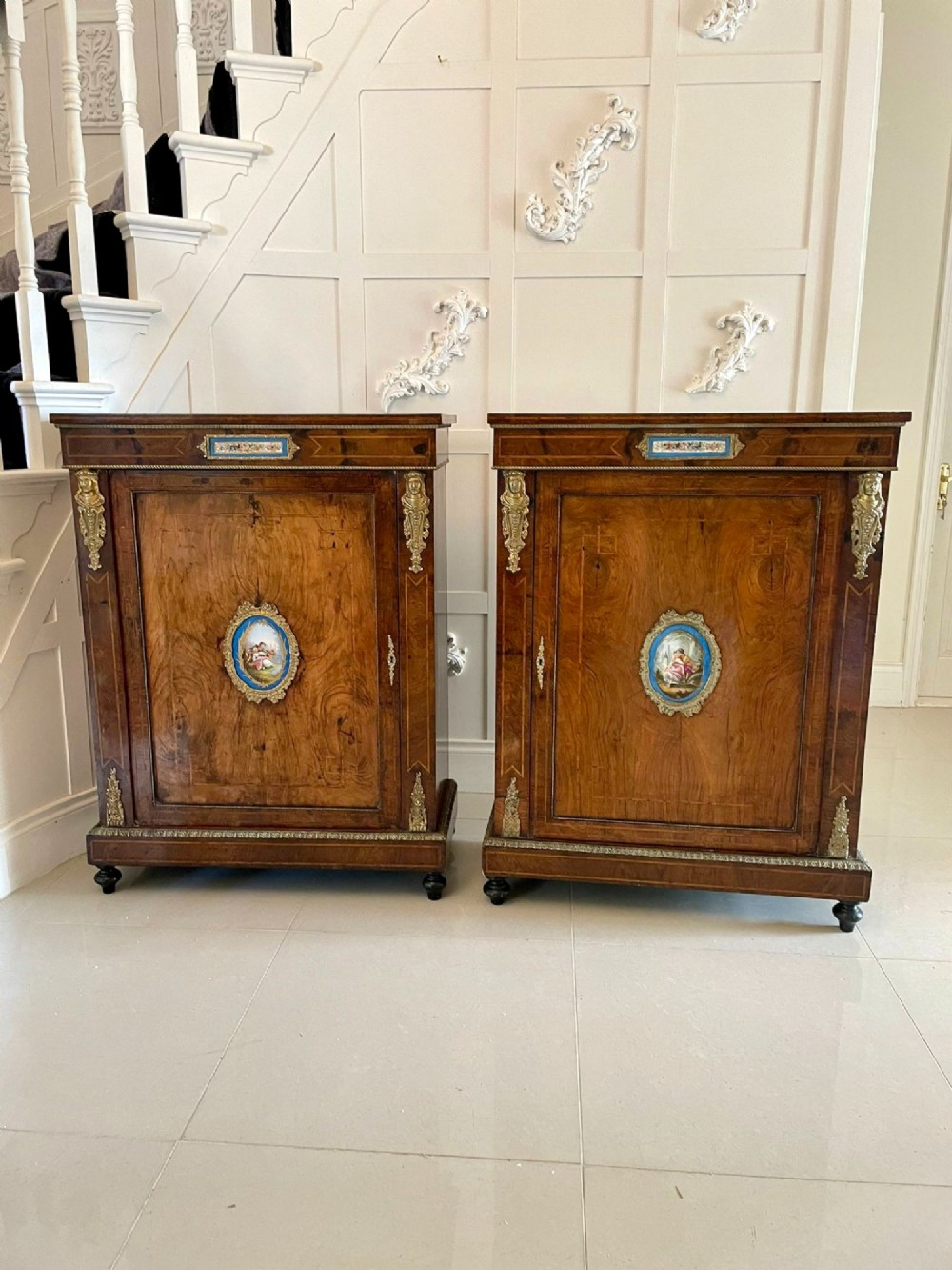 A pair of Victorian burr walnut pier cabinets featuring inlaid wood borders, gilt-bronze mounts, and central oval painted porcelain plaques. View XI