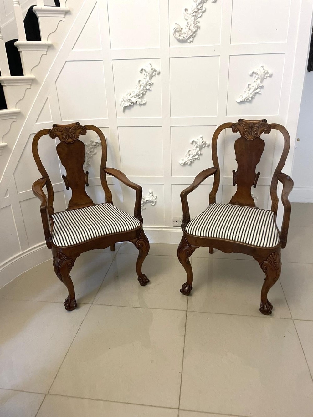 A set of twelve Victorian burr walnut dining chairs featuring carved splats, striped upholstered seats, and cabriole legs terminating in claw and ball feet. View VI