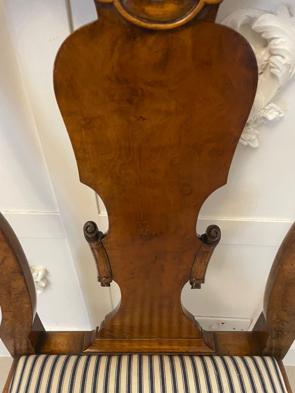 A set of twelve Victorian burr walnut dining chairs featuring carved splats, striped upholstered seats, and cabriole legs terminating in claw and ball feet. View X
