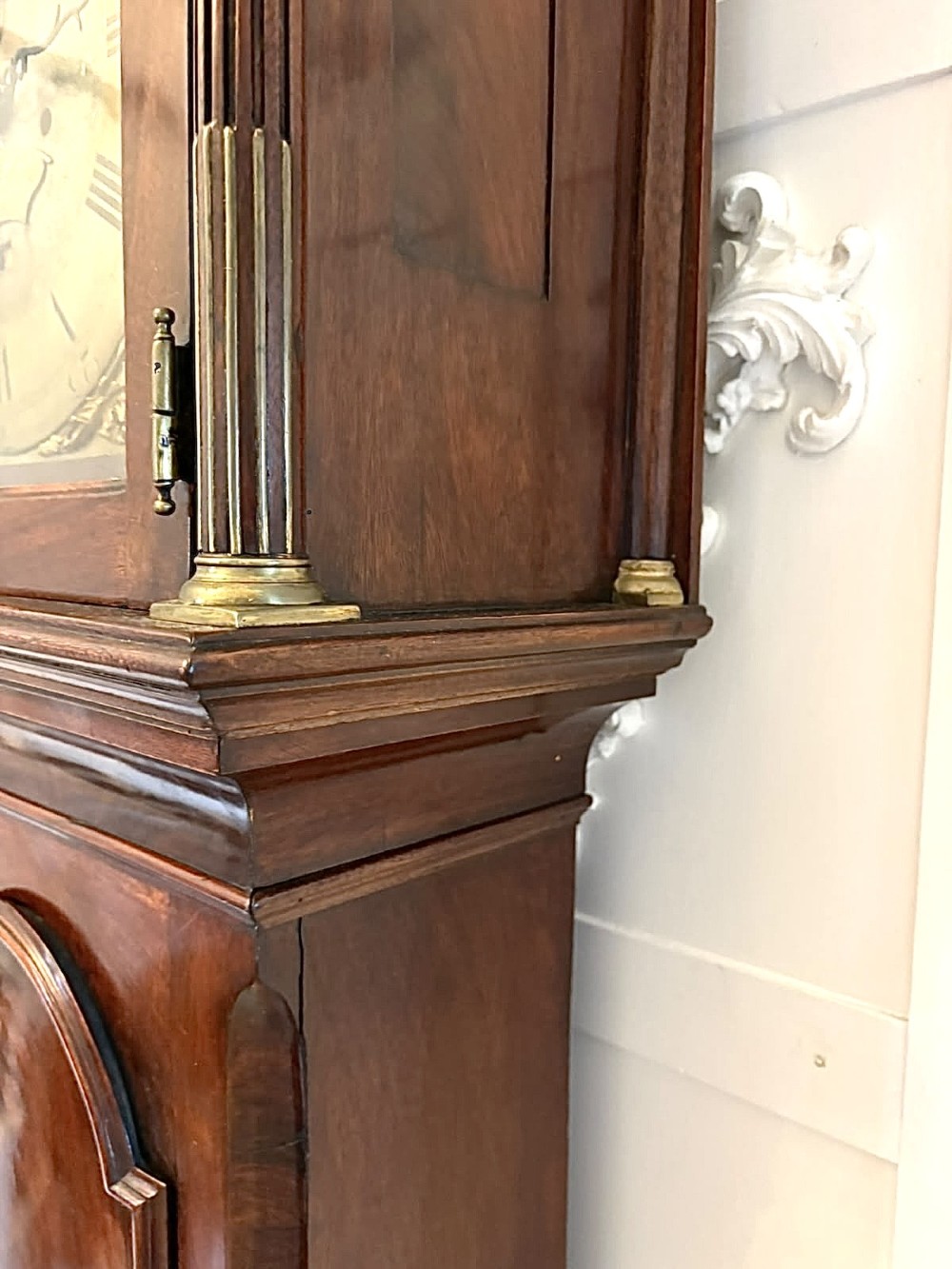 An antique Georgian longcase grandfather clock crafted from flame mahogany wood with an arched brass dial and brass finials. View V
