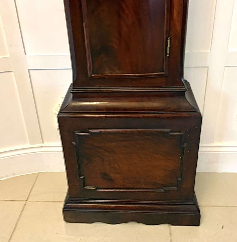 An antique Georgian longcase grandfather clock crafted from flame mahogany wood with an arched brass dial and brass finials. View VII