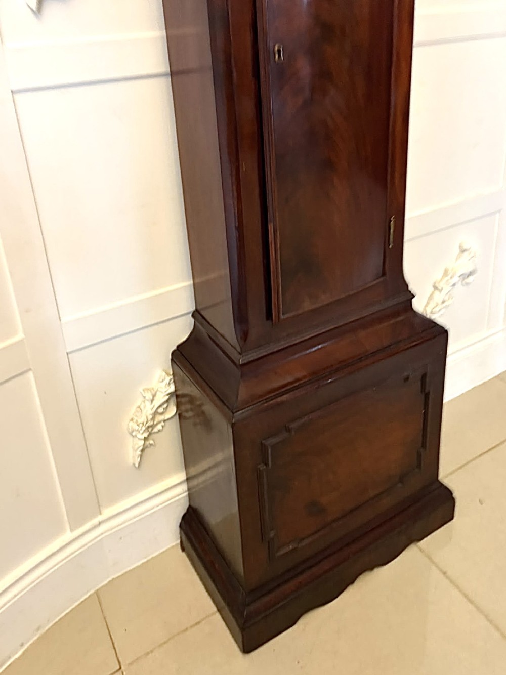 An antique Georgian longcase grandfather clock crafted from flame mahogany wood with an arched brass dial and brass finials. View VIII