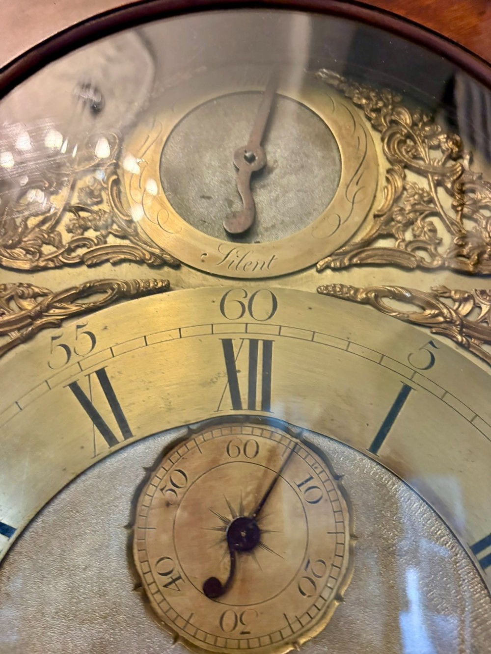 An antique Georgian longcase grandfather clock crafted from flame mahogany wood with an arched brass dial and brass finials. View IX